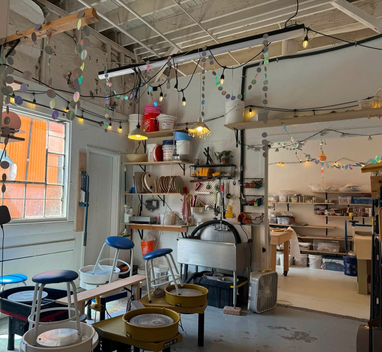 Pottery wheels, wash-up area, tools, and shelves inside the ceramics studio